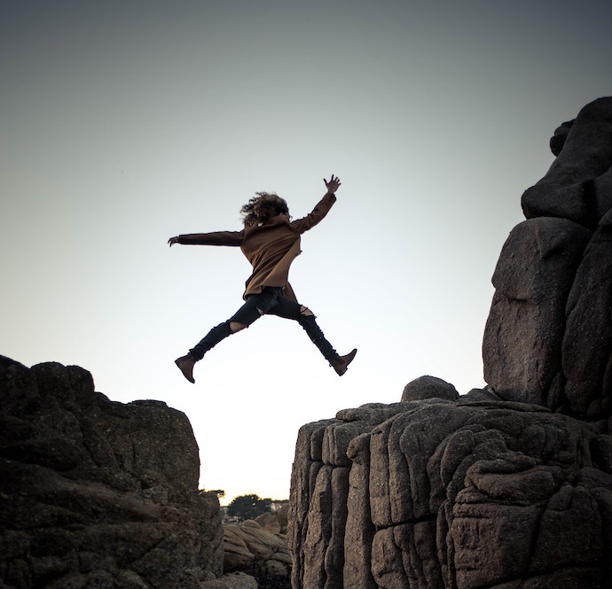 Woman jumping over ravine