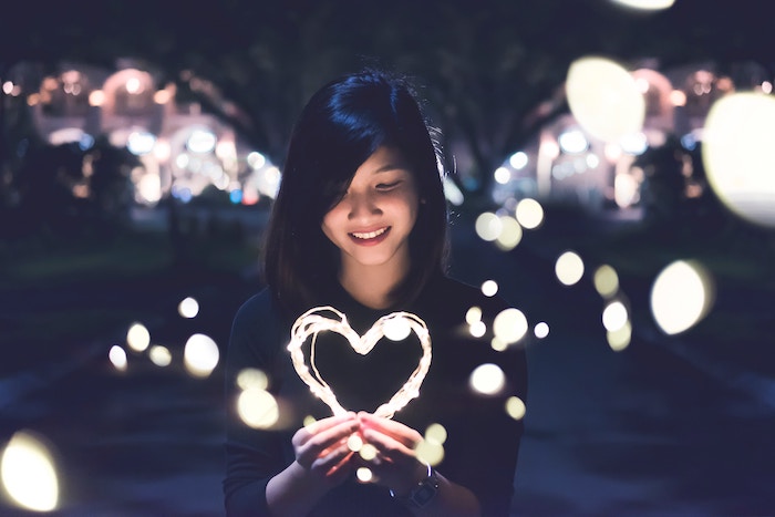 Woman is holding a heart shaped light