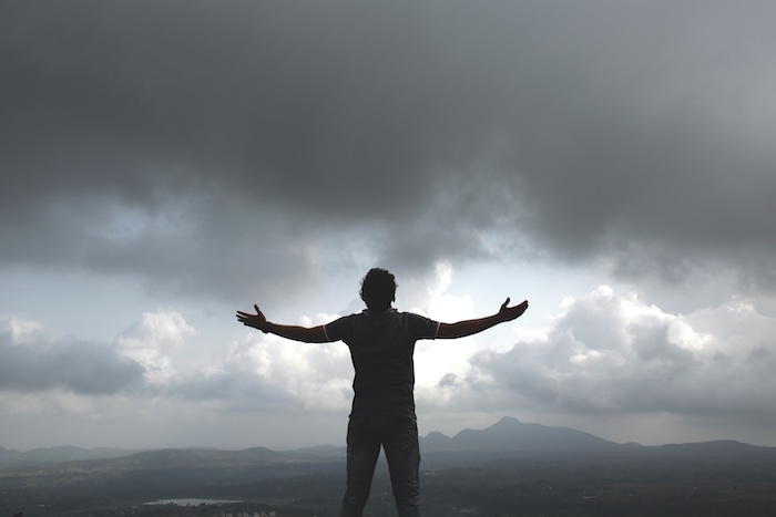 Man standing on top of a hill facing the weather