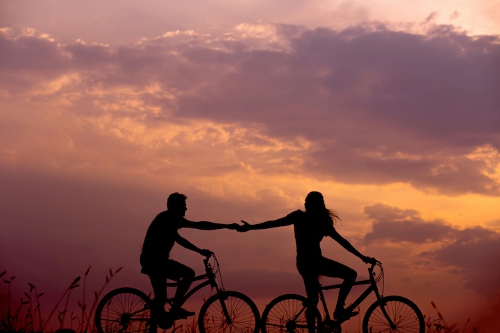 A couple on bicycles in the sunset