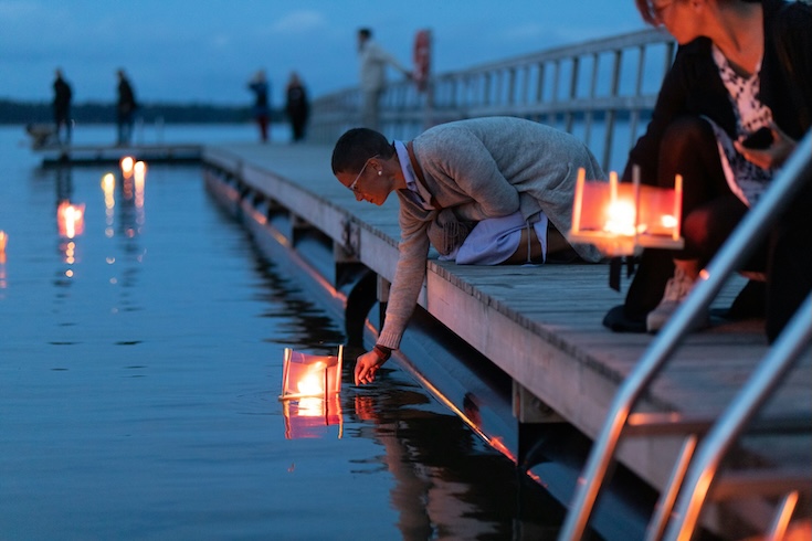 Person setting a floating candle onto the water