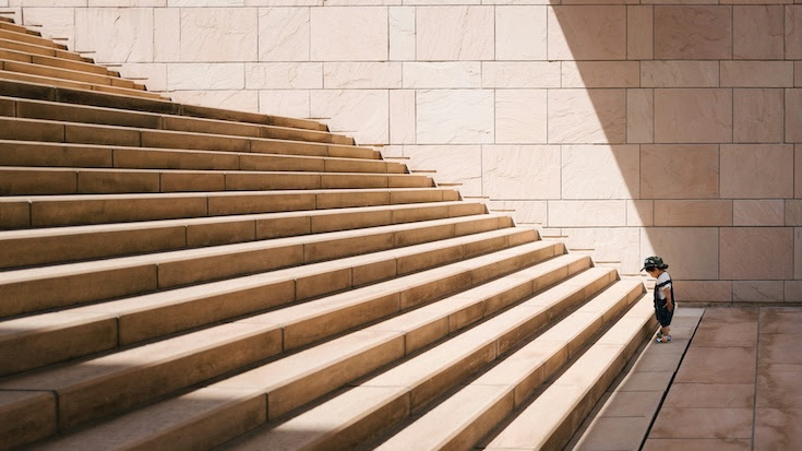 A kid standing in front of giant stairs