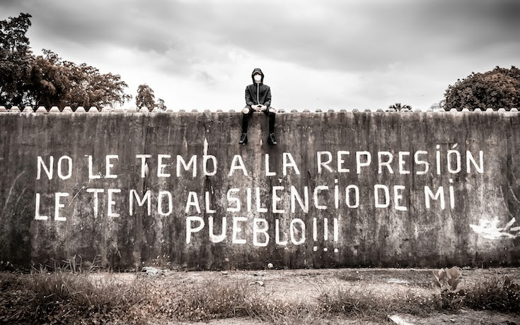 Man sitting on a wall with writing on it