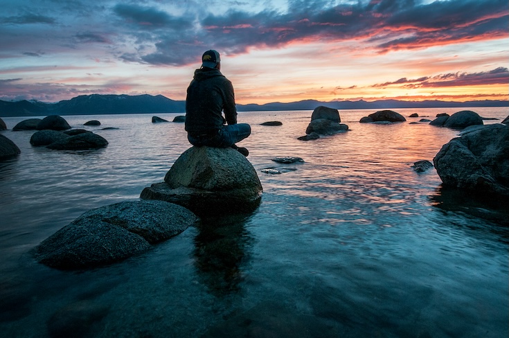 Man sitting on a rock in the water
