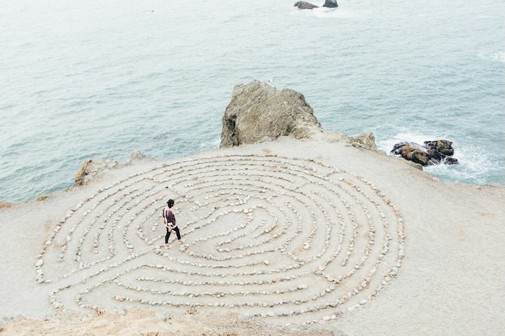 Person walking a maze made of stones next to the ocean